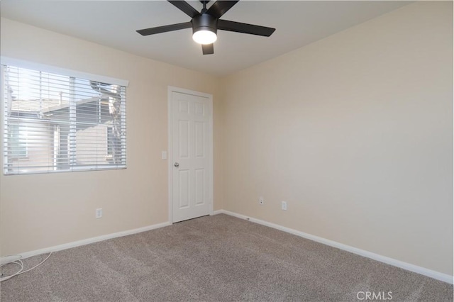 carpeted spare room with baseboards and a ceiling fan