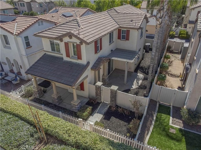 exterior space featuring a fenced front yard, a tile roof, stucco siding, a gate, and a residential view