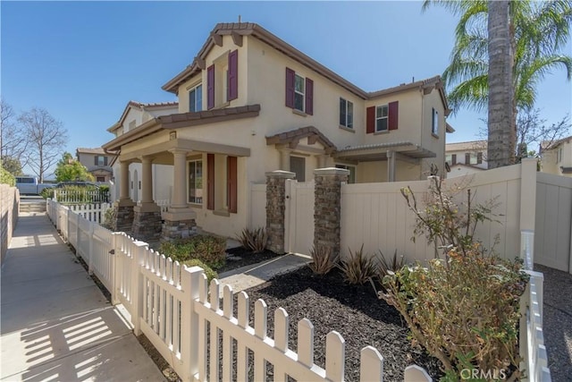 view of front of house with a tiled roof, a fenced front yard, a gate, and stucco siding