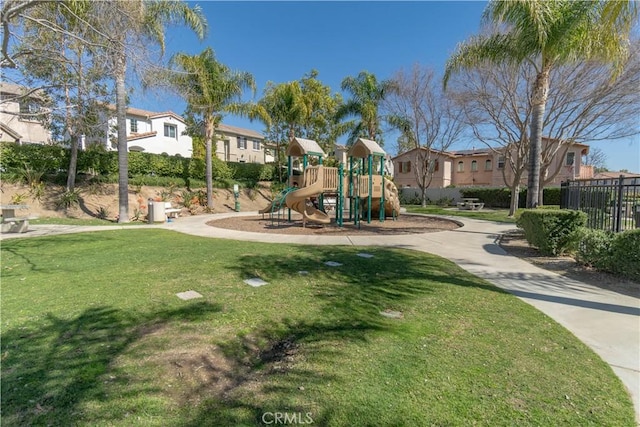 community playground featuring a yard, fence, and a residential view