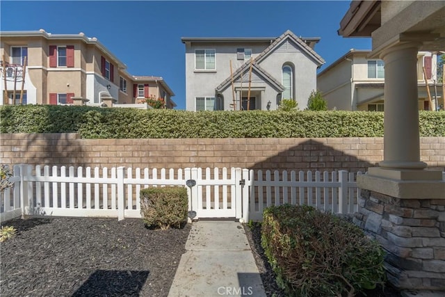 view of front facade featuring a fenced front yard, a gate, and stucco siding