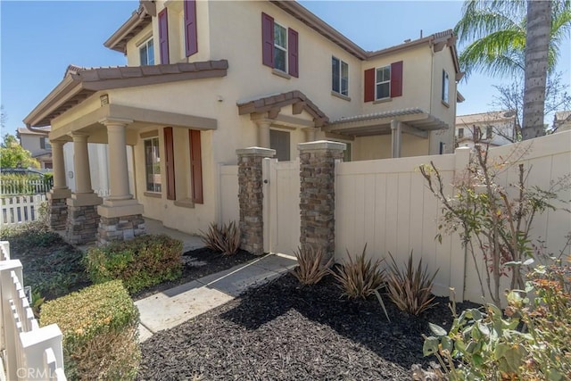 view of property exterior with a fenced front yard, a gate, and stucco siding