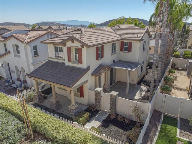 view of front of home featuring a patio area, a fenced backyard, a mountain view, and stucco siding