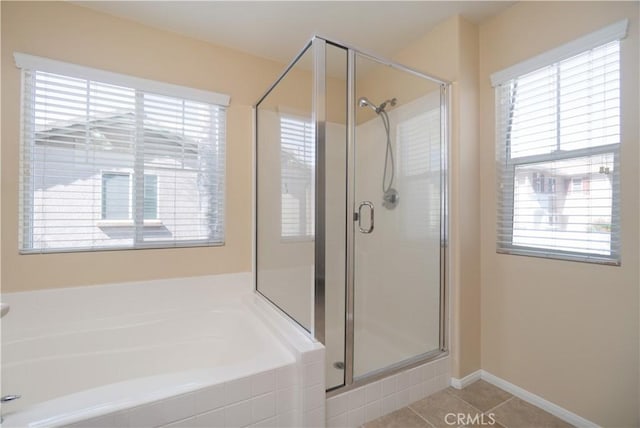 bathroom with baseboards, a stall shower, a bath, and tile patterned floors