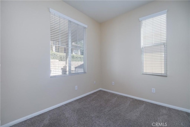 empty room featuring carpet and baseboards