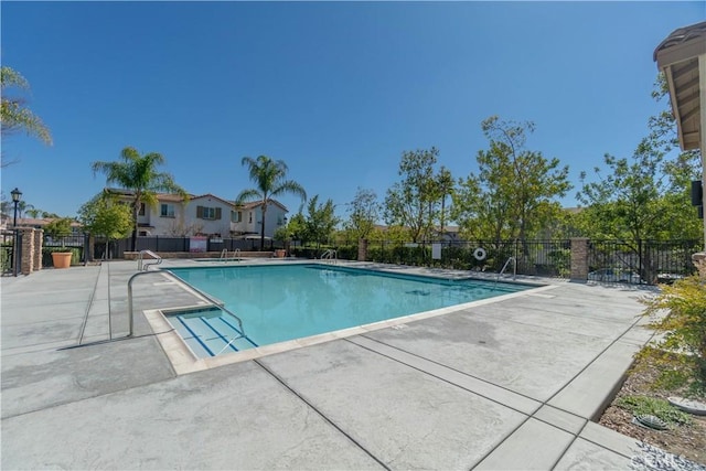 community pool with a patio and fence