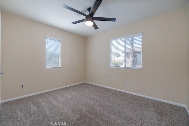 carpeted spare room featuring ceiling fan and baseboards