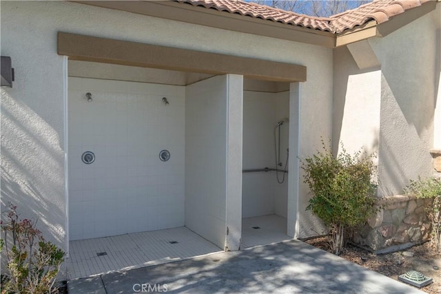 doorway to property with a tiled roof and stucco siding