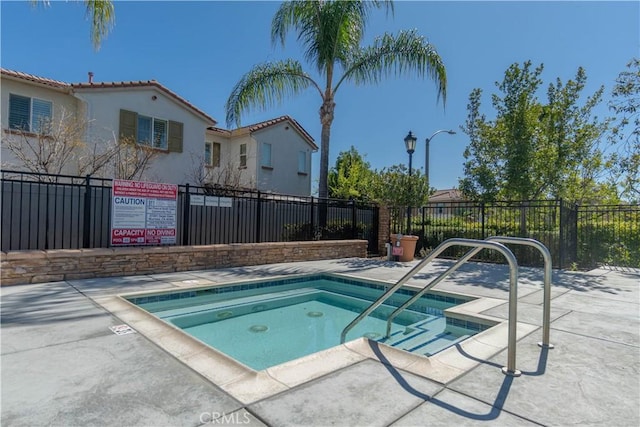 view of swimming pool featuring fence and a community hot tub