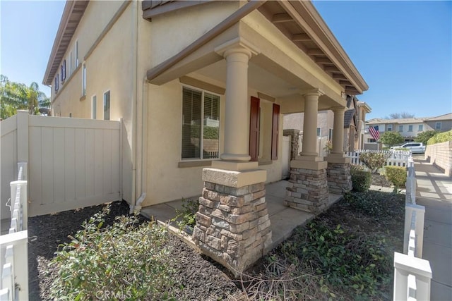 exterior space with fence, a porch, and stucco siding