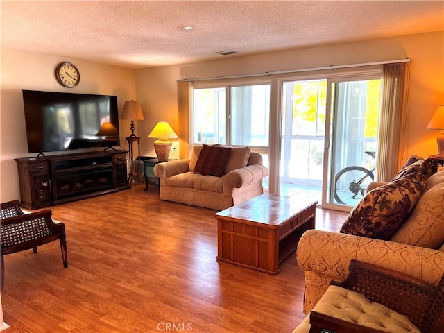 living room with visible vents, a textured ceiling, and wood finished floors