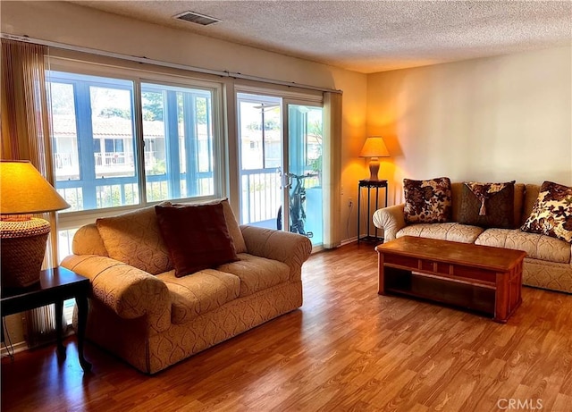 living area featuring a textured ceiling, wood finished floors, and visible vents