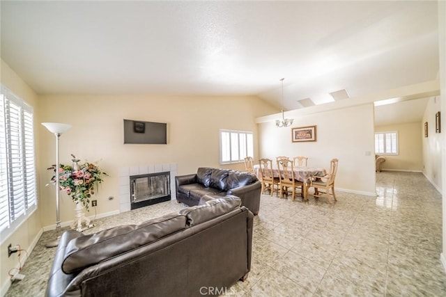 living area with lofted ceiling, a fireplace, baseboards, and a notable chandelier