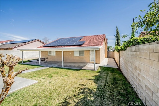 back of house featuring a patio, a fenced backyard, a tile roof, roof mounted solar panels, and stucco siding