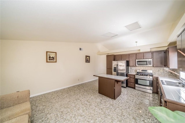 kitchen with tile countertops, tasteful backsplash, appliances with stainless steel finishes, open floor plan, and a sink