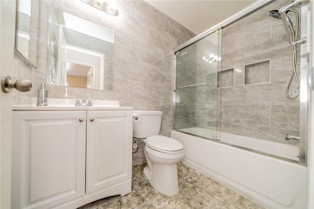 bathroom featuring vanity, tile walls, toilet, and bath / shower combo with glass door