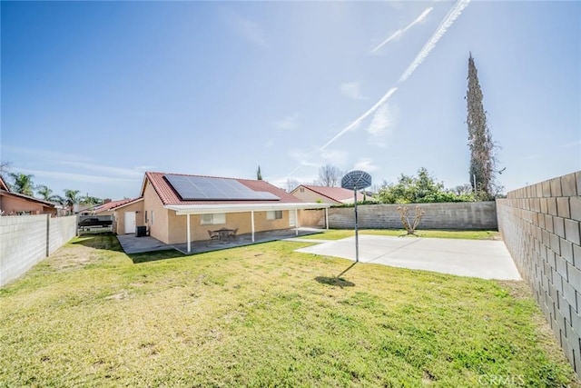 back of property featuring a patio, a fenced backyard, and roof mounted solar panels