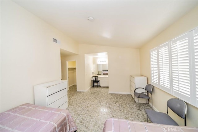 bedroom with vaulted ceiling, a spacious closet, visible vents, and baseboards