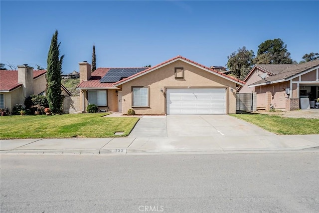 view of front of home featuring a garage, solar panels, driveway, stucco siding, and a front lawn