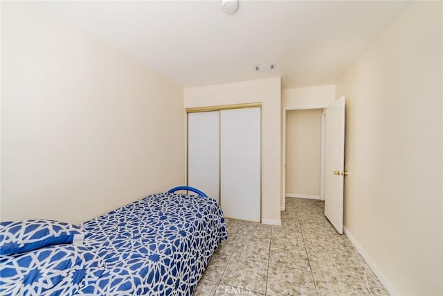 bedroom featuring a closet, visible vents, baseboards, and light tile patterned floors