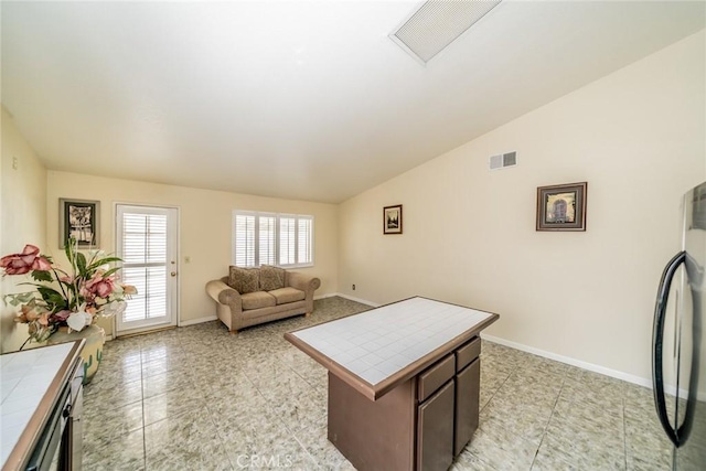 living room with visible vents, vaulted ceiling, baseboards, and light tile patterned floors