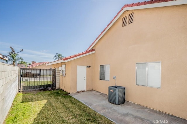 back of property featuring a yard, stucco siding, central AC, fence, and a tiled roof