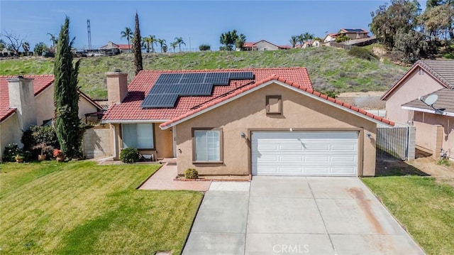 view of front of house with stucco siding, concrete driveway, a front yard, roof mounted solar panels, and a tiled roof