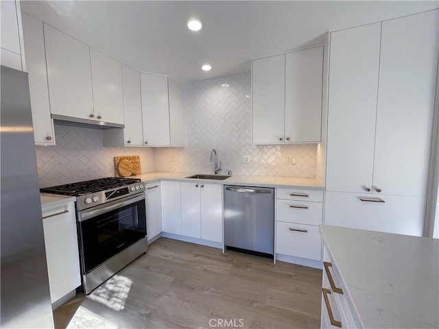 kitchen with appliances with stainless steel finishes, white cabinets, light countertops, and a sink