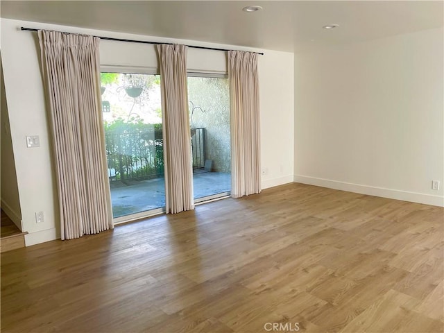 unfurnished room featuring recessed lighting, wood finished floors, and baseboards