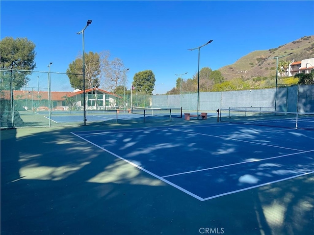 view of tennis court featuring fence and a mountain view