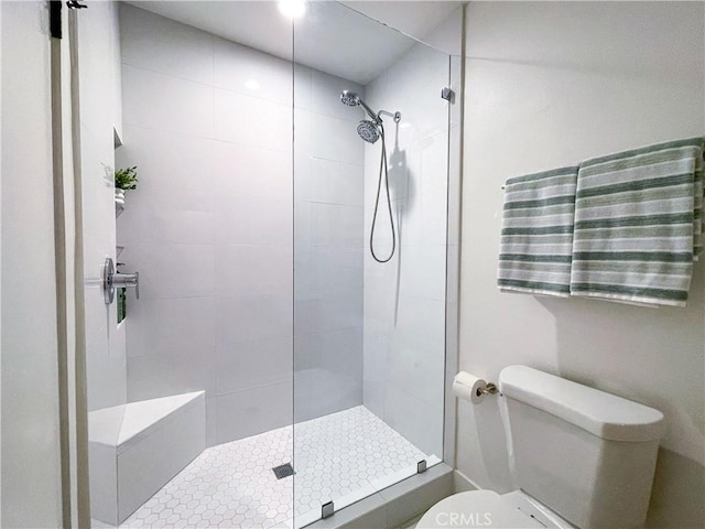 full bathroom with a tile shower and toilet