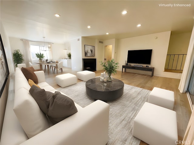 living area with recessed lighting, visible vents, a fireplace with raised hearth, and light wood-style flooring