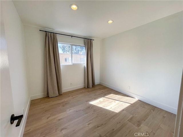 spare room featuring recessed lighting, light wood-style flooring, and baseboards