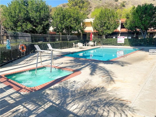 community pool with fence and a patio