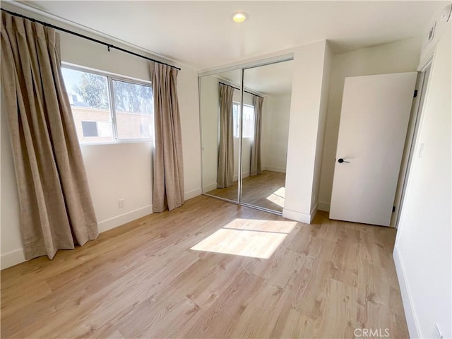 unfurnished bedroom featuring a closet, light wood-style flooring, and baseboards