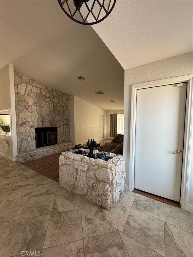 living room featuring lofted ceiling, visible vents, and a fireplace