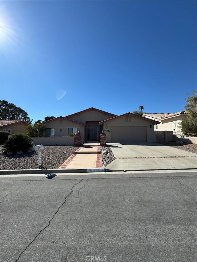 view of front facade with a garage, driveway, and fence