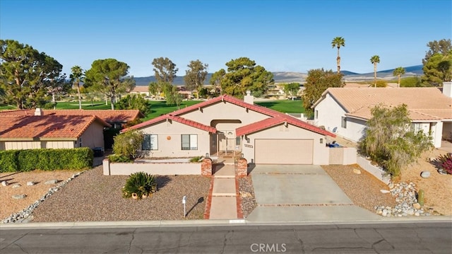 view of front facade with concrete driveway, an attached garage, a mountain view, and stucco siding