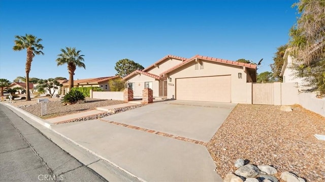 mediterranean / spanish home with fence, stucco siding, concrete driveway, a garage, and a tiled roof