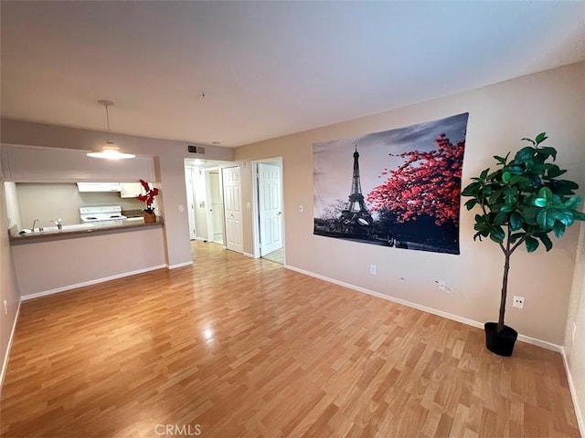 unfurnished living room featuring visible vents, baseboards, and wood finished floors