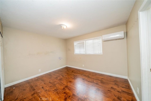 unfurnished room with wood finished floors, baseboards, and a wall mounted AC