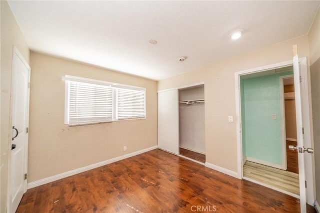 unfurnished bedroom featuring a closet, baseboards, and wood finished floors