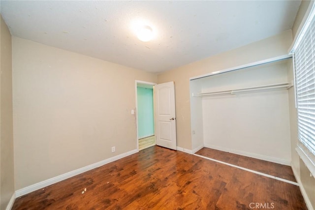 unfurnished bedroom with a closet, baseboards, and wood finished floors