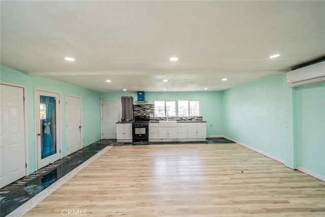 kitchen featuring extractor fan, recessed lighting, a wall mounted air conditioner, light wood finished floors, and gas stove