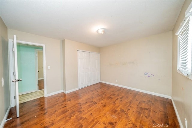 unfurnished bedroom with a closet, baseboards, and wood finished floors