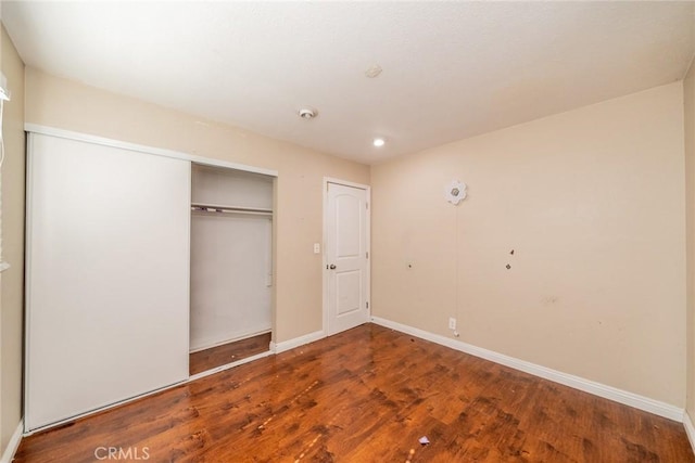 unfurnished bedroom featuring a closet, recessed lighting, wood finished floors, and baseboards