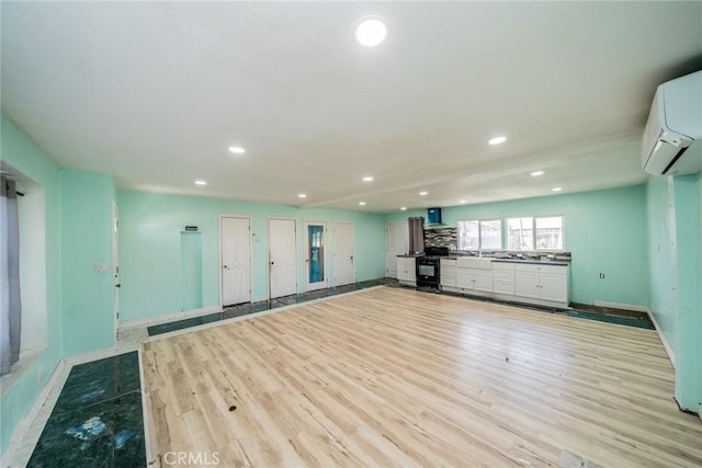 interior space featuring baseboards, an AC wall unit, light wood-style flooring, and recessed lighting