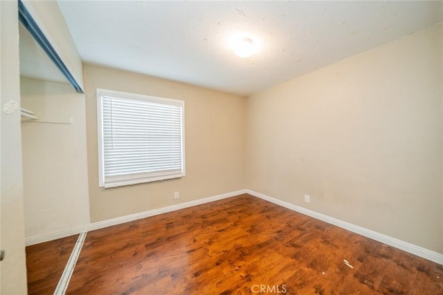 empty room with baseboards and wood finished floors