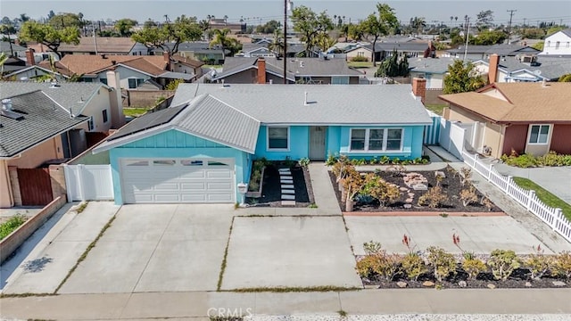 view of front facade with a garage, a residential view, driveway, and fence private yard