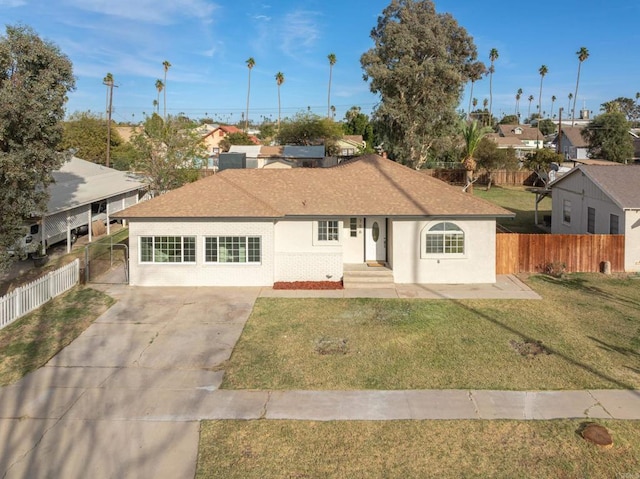 ranch-style home with a shingled roof, fence, a front lawn, and stucco siding